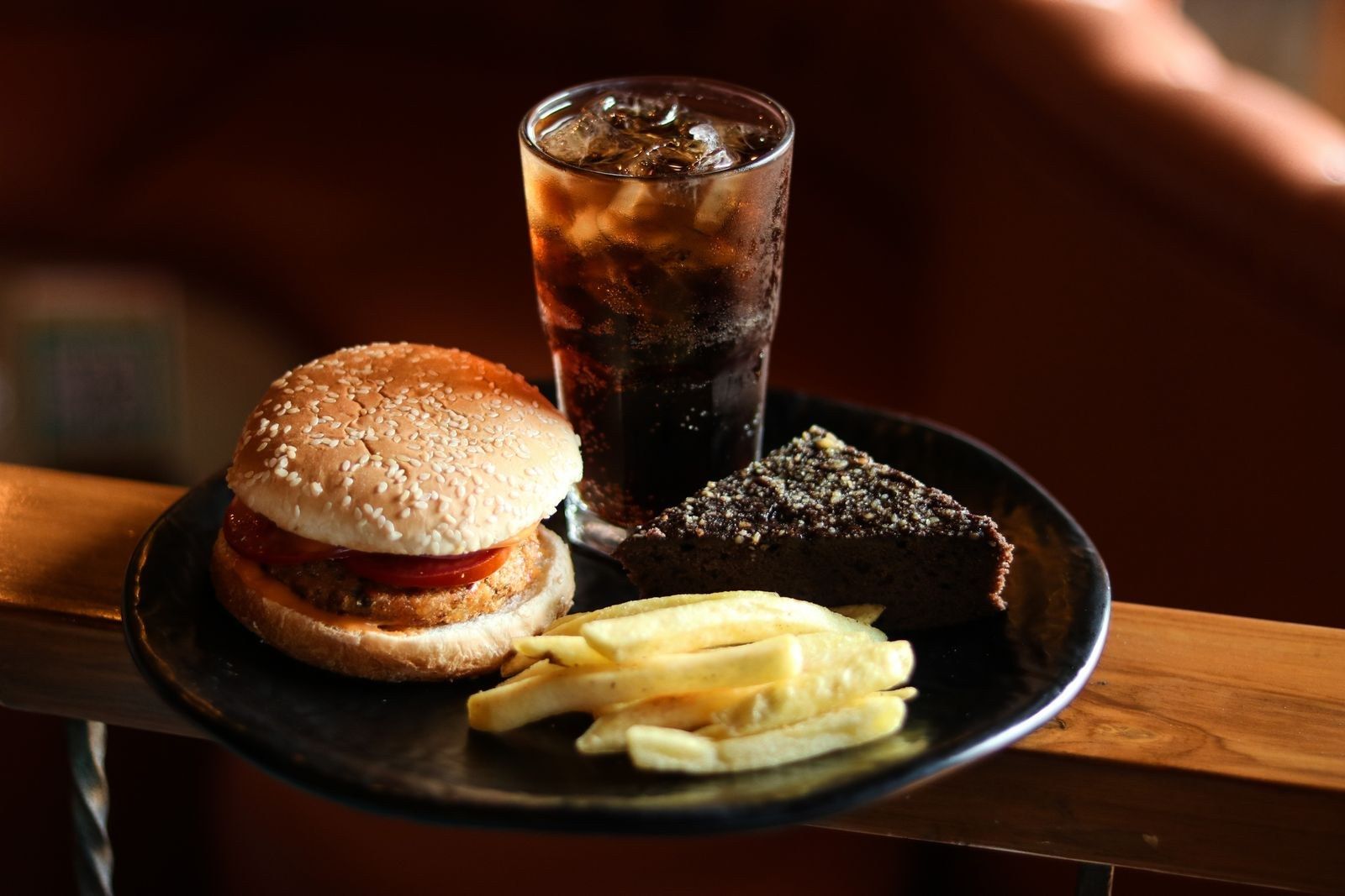 Combo de lanche, batata frita e refrigerante sobre mesa de madeira escura