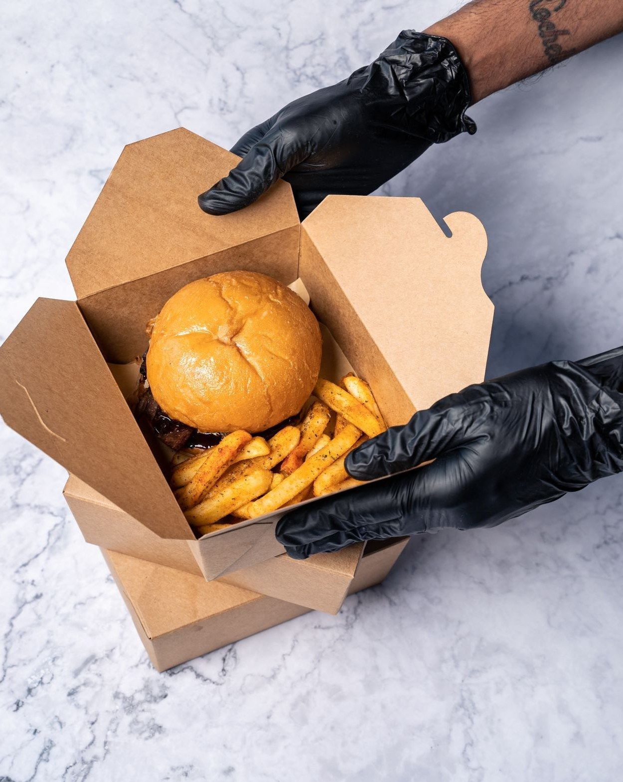 Caixa de delivery aberta, com o lanche sendo entregue